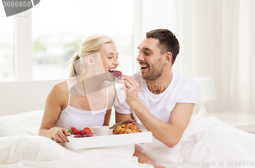 Image of happy couple having breakfast in bed at home