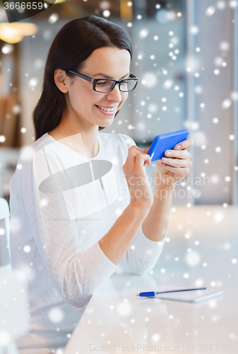 Image of smiling woman with smartphone at cafe