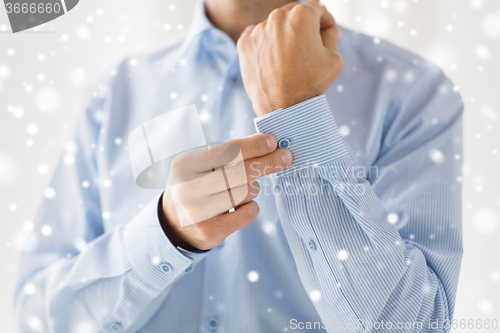 Image of close up of man fastening button on shirt sleeve