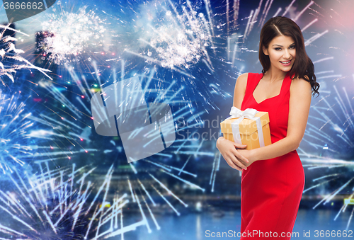 Image of happy woman in red dress with gift over firework