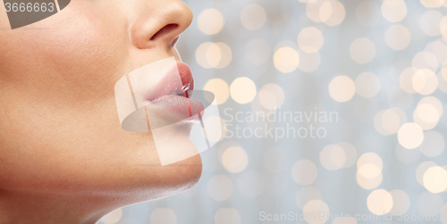 Image of close up of young woman lips over holidays lights
