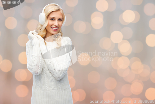 Image of smiling young woman in winter earmuffs and sweater