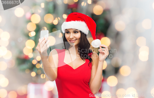 Image of woman in santa hat taking selfie by smartphone