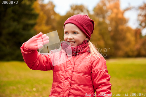 Image of happy little girl waving hand in autumn park