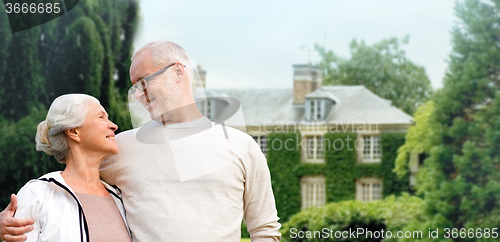 Image of senior couple hugging over living house background