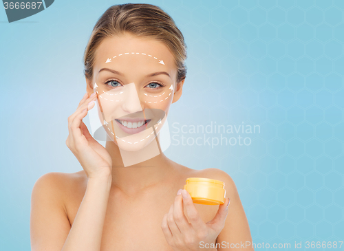 Image of happy young woman applying cream to her face