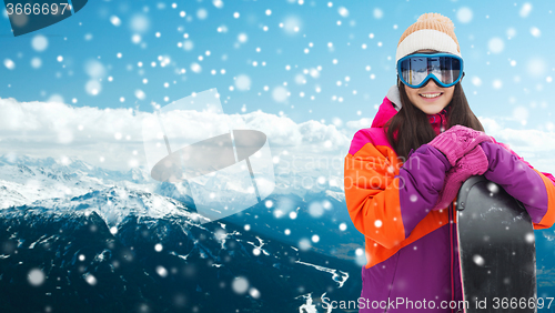 Image of happy young woman with snowboard over mountains
