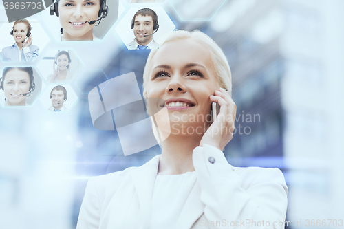 Image of smiling businesswoman with smartphone outdoors