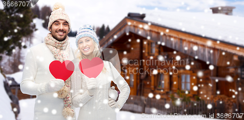 Image of happy couple in winter clothes with heart outdoors