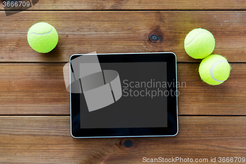 Image of close up of tennis balls and tablet pc on wood