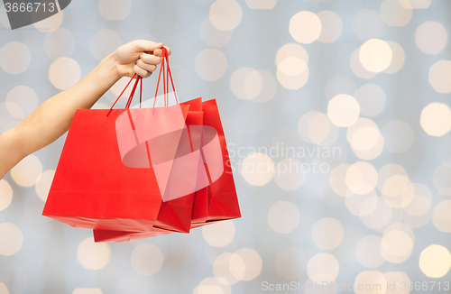 Image of close up of hand holding red shopping bags