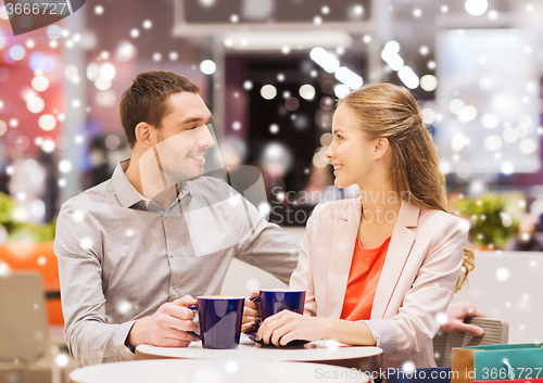 Image of happy couple with shopping bags drinking coffee