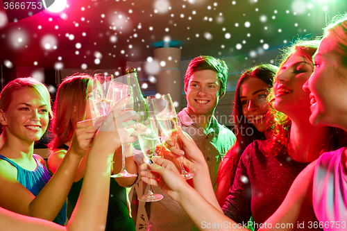 Image of smiling friends with glasses of champagne in club