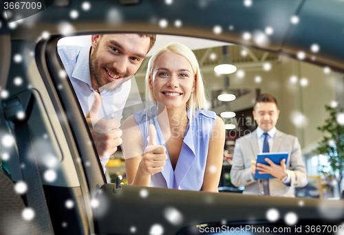 Image of happy couple with car dealer in auto show or salon