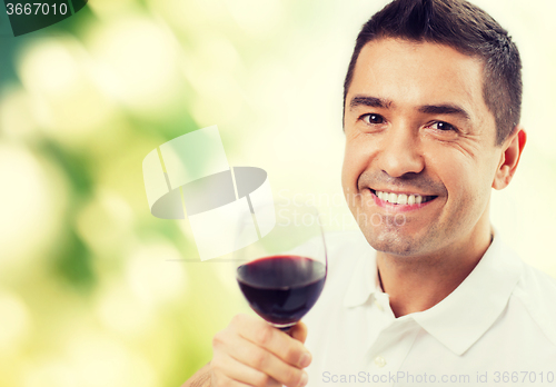 Image of happy man drinking red wine from glass