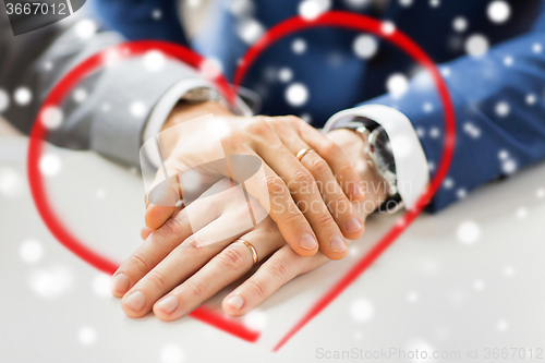 Image of close up of gay couple hands with wedding rings on