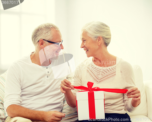 Image of happy senior couple with gift box at home