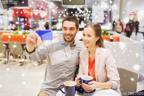 Image of happy couple with smartphone taking selfie in mall