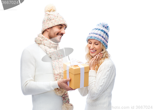 Image of smiling couple in winter clothes with gift box