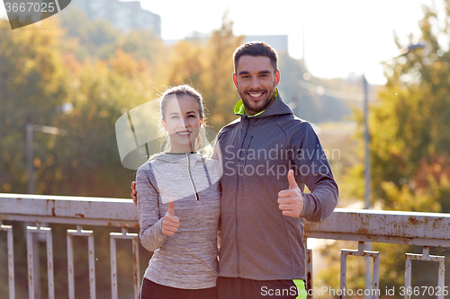 Image of smiling couple showing thumbs up outdoors