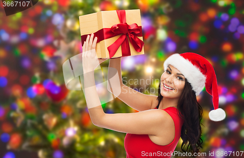 Image of beautiful woman in santa hat with gift over lights