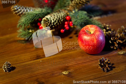 Image of close up of apple with fir decoration on wood