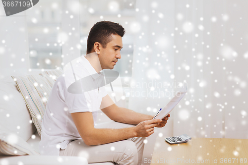 Image of man with papers and calculator at home