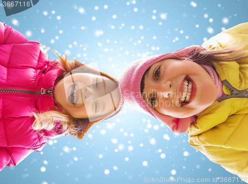 Image of happy little girls faces over blue sky and snow