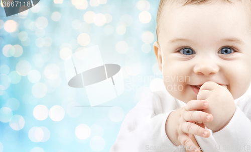 Image of happy baby face over blue holidays lights