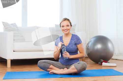 Image of happy woman with water bottle exercising at home