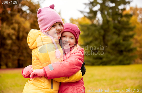 Image of two happy little girls hugging in autumn park