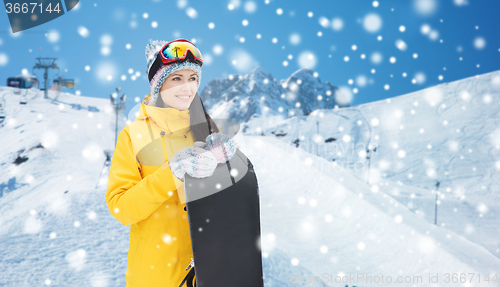 Image of happy young woman with snowboard over mountains