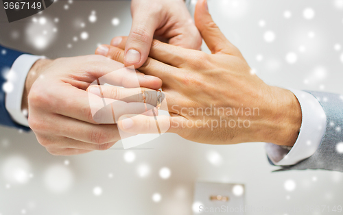 Image of close up of male gay couple hands and wedding ring