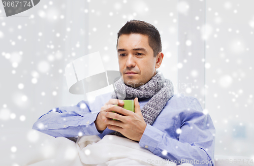 Image of ill man with flu drinking hot tea from cup at home