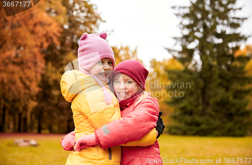 Image of two happy little girls hugging in autumn park