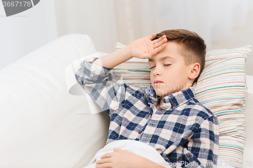 Image of ill boy lying in bed and suffering from headache