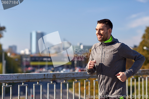 Image of happy young man running over city bridge