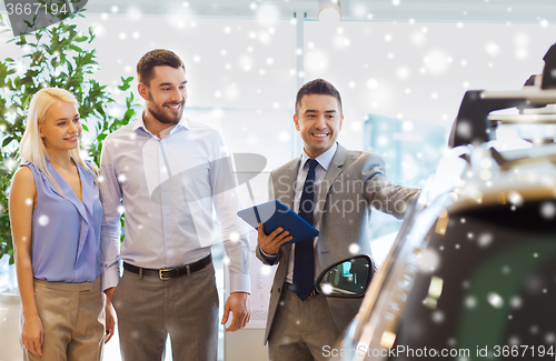 Image of happy couple with car dealer in auto show or salon