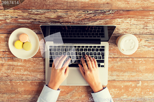 Image of close up of female hands with laptop and coffee