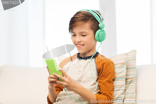 Image of happy boy with smartphone and headphones at home