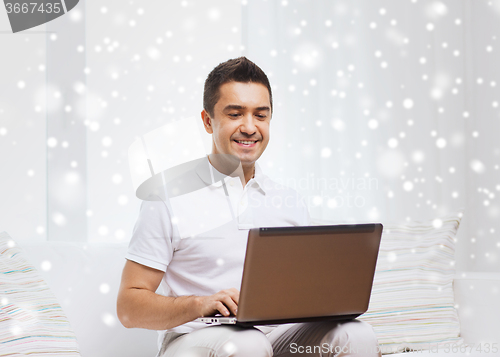 Image of happy man working with laptop computer at home