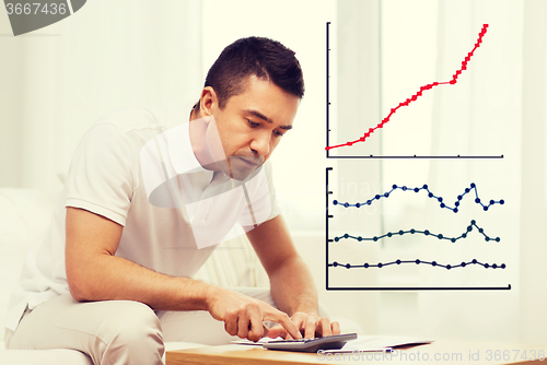 Image of man with papers and calculator at home