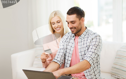 Image of happy couple with laptop and credit card at home