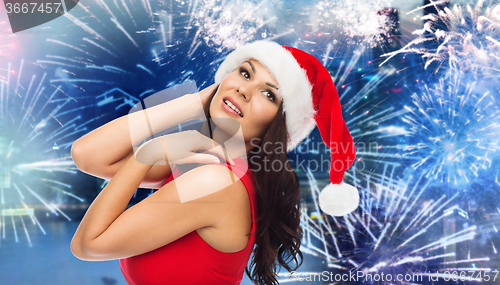 Image of woman in santa hat and red dress over firework