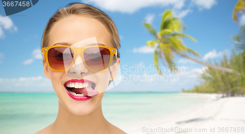 Image of happy young woman in sunglasses showing tongue