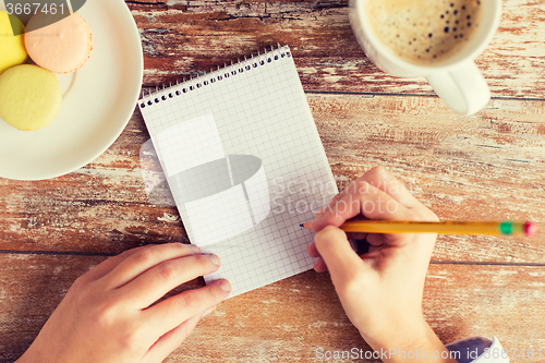 Image of close up of hands, notebook, coffee and cookies