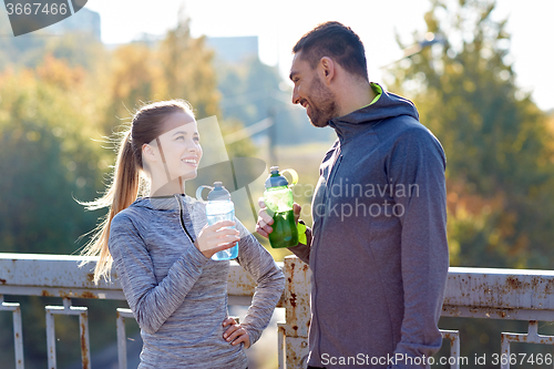 Image of smiling couple with bottles of water outdoors