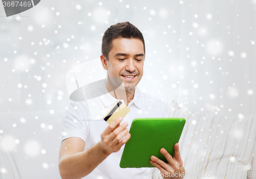 Image of smiling man working with tablet pc and credit card