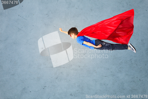 Image of boy in red superhero cape and mask flying on air