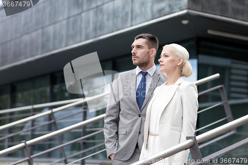 Image of serious businessmen standing over office building